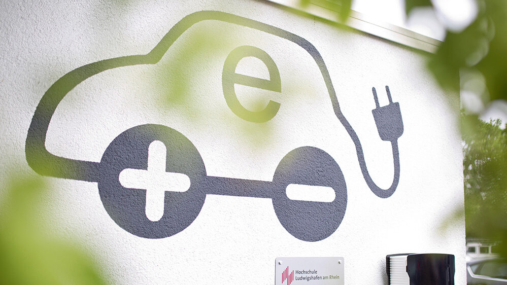 Das Bild zeigt eine stilisierte Darstellung eines Elektroautos mit einem Ladekabel, platziert an einer Wand.