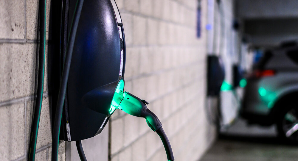 Eine Ladestation für Elektrofahrzeuge an einer Wand, mit einem grünen Licht, das den Ladevorgang anzeigt.