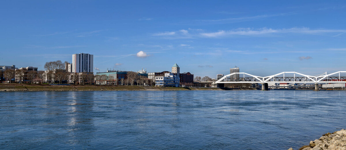 Die Szene zeigt einen klaren Fluss, der sanft fließt, umgeben von städtischen Strukturen und einer Brücke im Hintergrund.