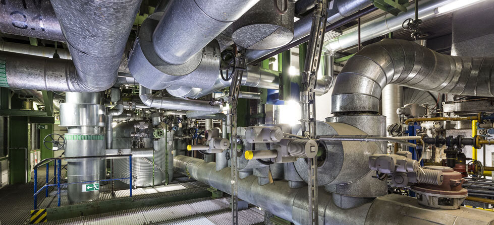 Ein komplexes Rohrleitungssystem in einer industriellen Umgebung, das aus verschiedenen Metallrohren und Ventilen besteht.