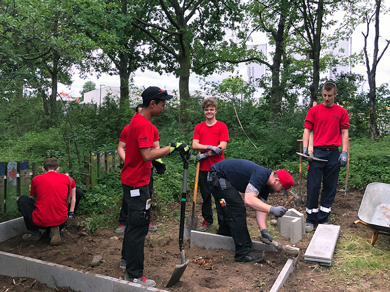 Eine Gruppe von Männern arbeiten gemeinsam im Freien, um eine Gartenlandschaft zu gestalten.